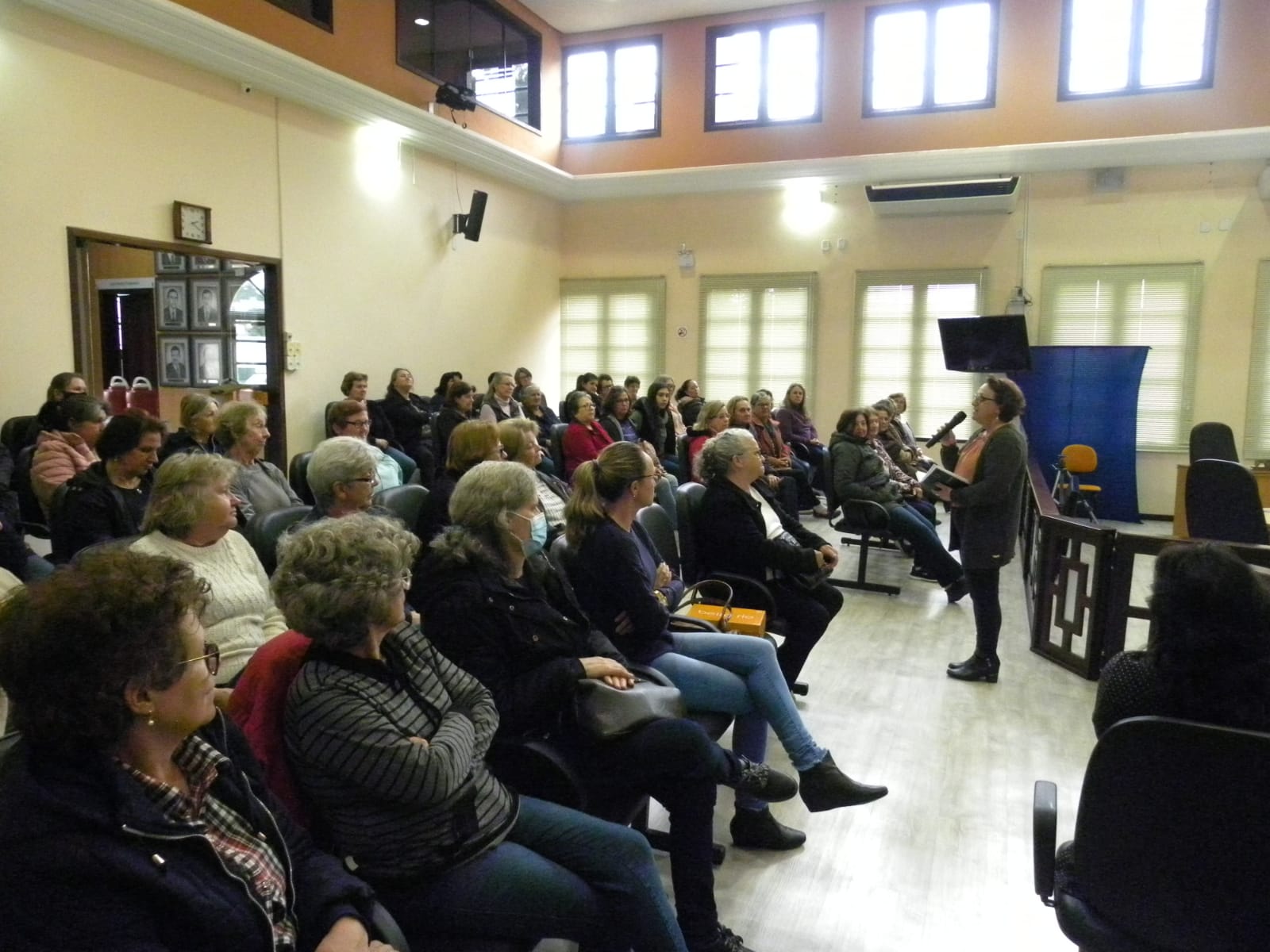 Mulheres sentadas em reunião escutando palestrante