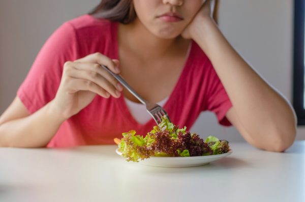 Imagem de uma pessoa, vestindo uma roupa vermelha, prestes a comer uma salada.
