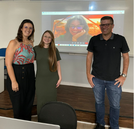 Maria Fernanda Uller, estudante de jornalismo, com os professores Marina Adriano de Andrade, João Kamradt e Kérley Winques, que está com a imagem projetada no fundo.